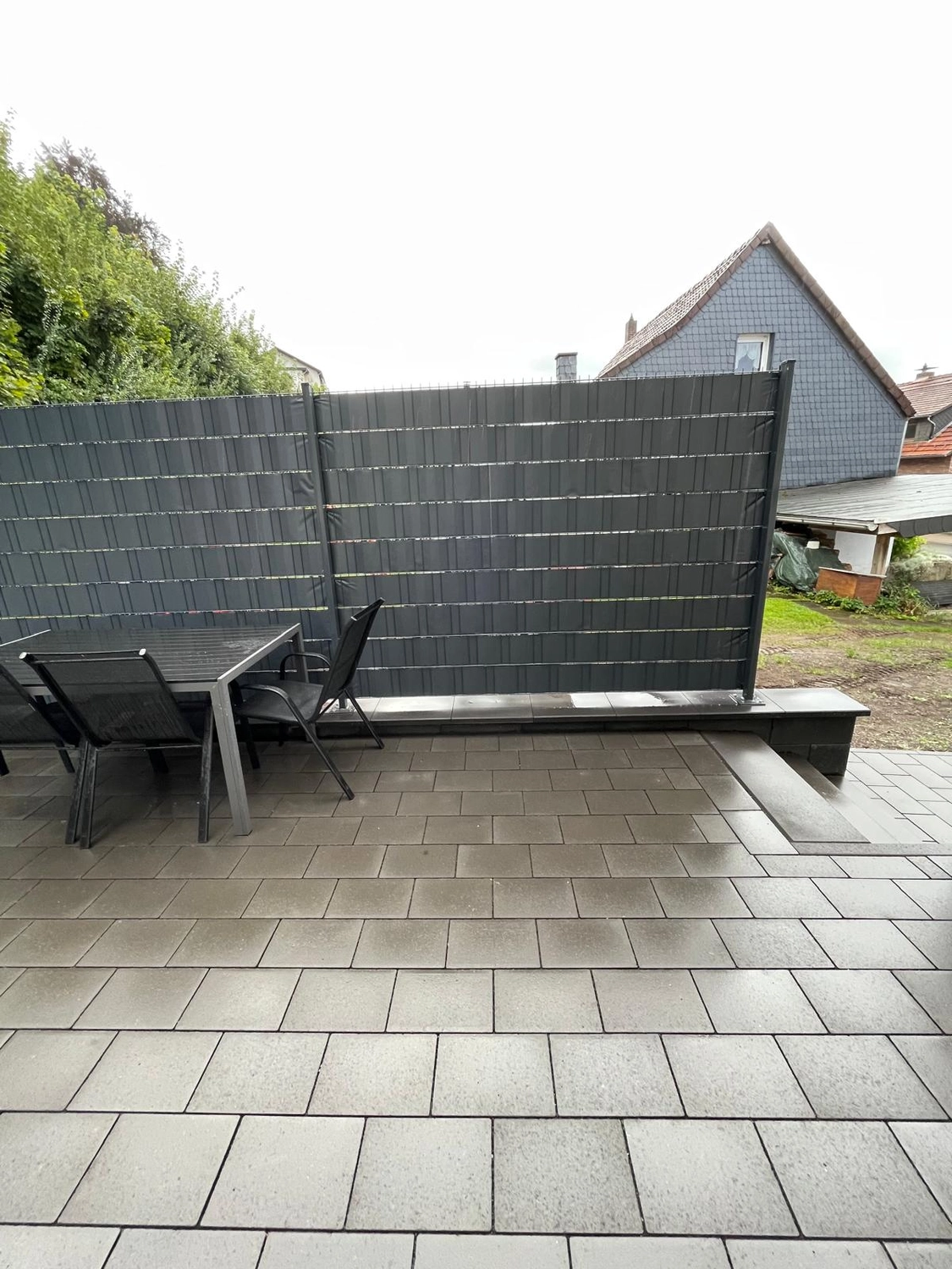 WPC-Sichtschutzzaun um eine gepflasterte Terrasse